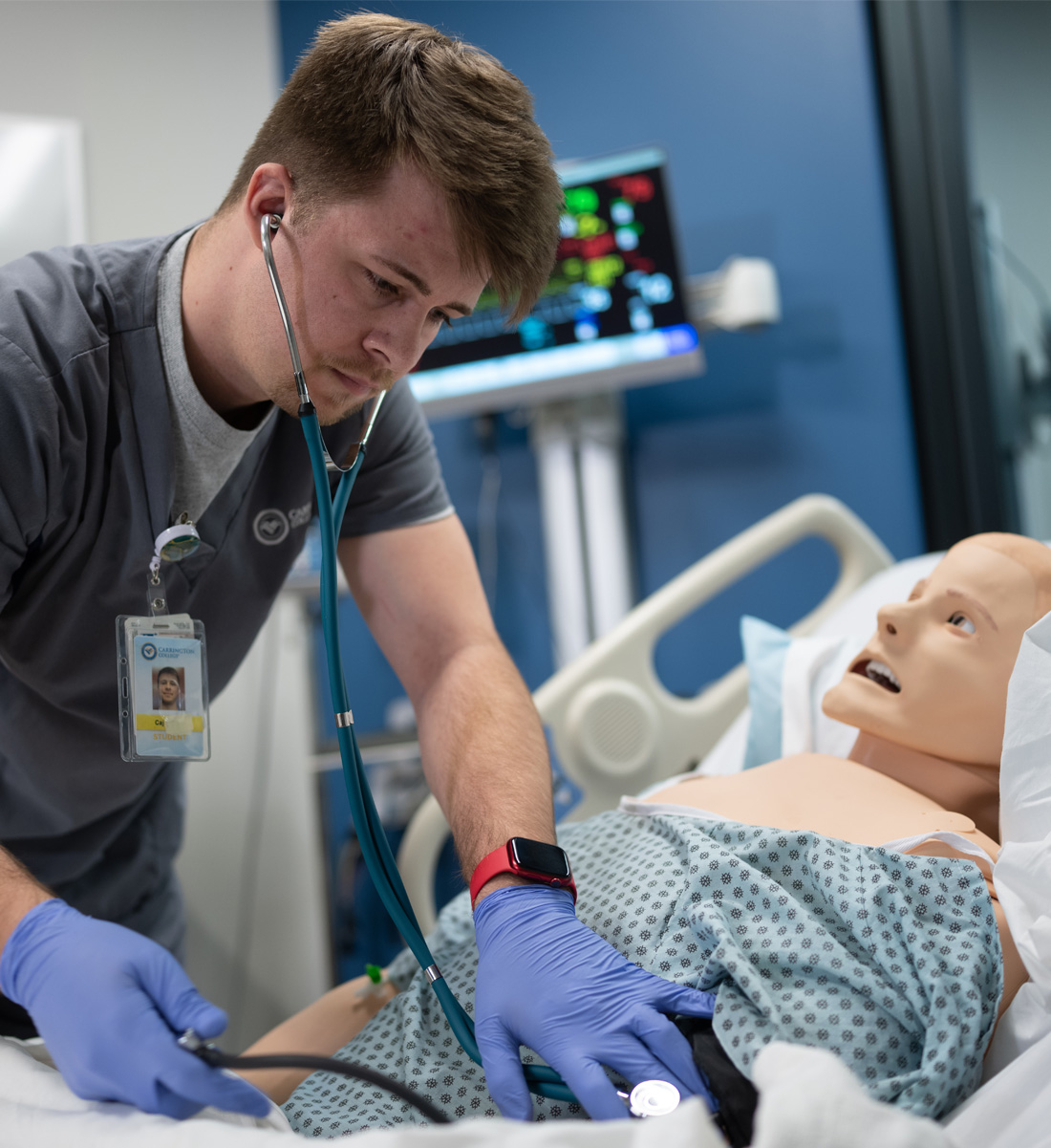 Carrington College medical student using stethoscope on practice dummy patient