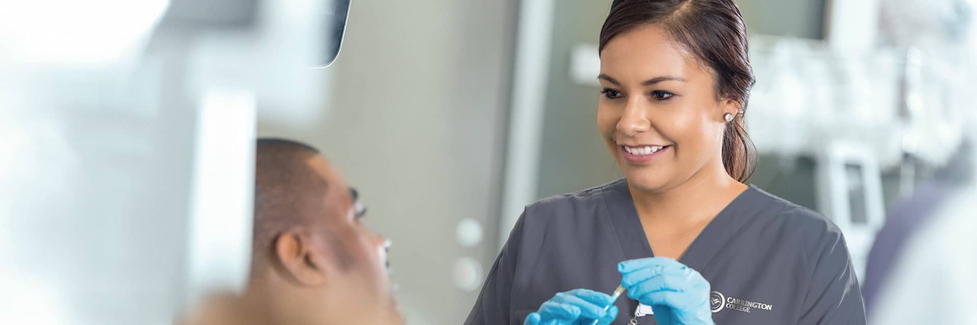 Young woman in scrubs and gloves with male patient.