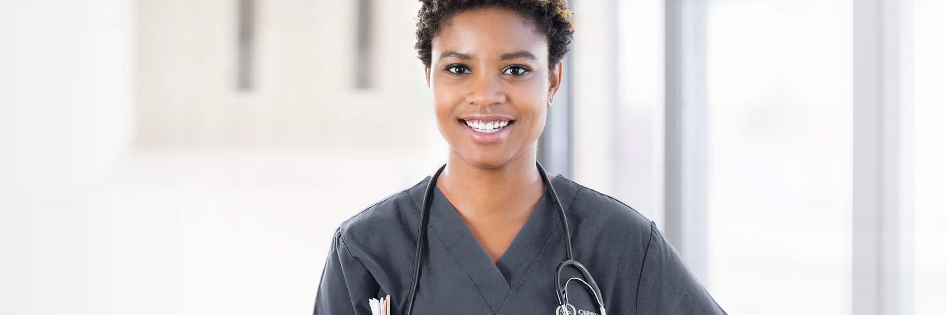 Young woman in dark scrubs with a stethoscope.