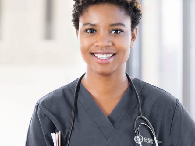 Young woman in dark scrubs with a stethoscope.