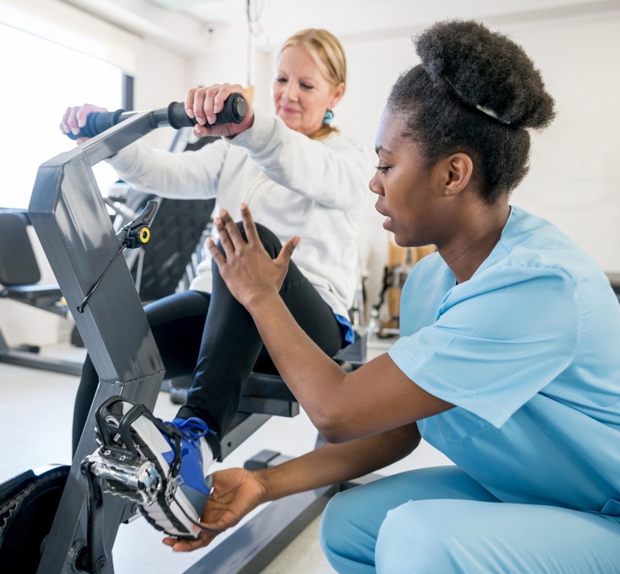 Physical therapist assisting patient on exercise bike