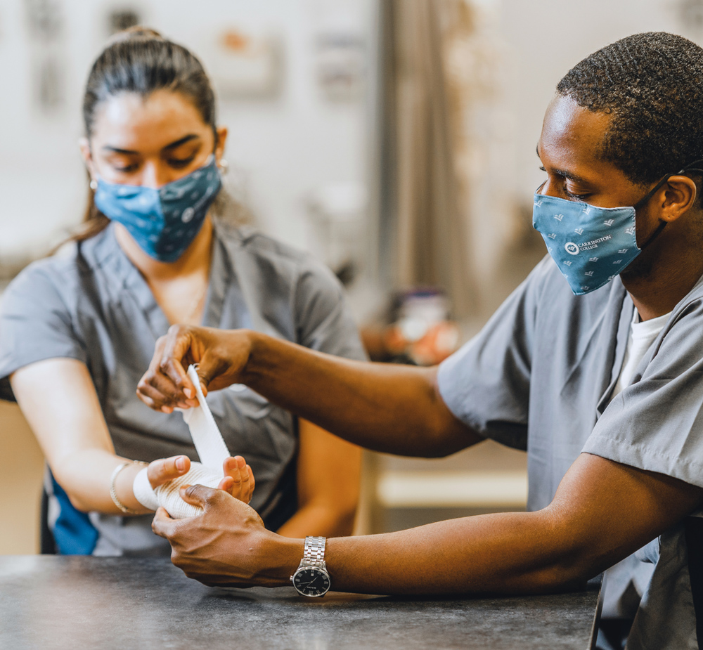 Carrington College nursing students practicing gauze application on the hand