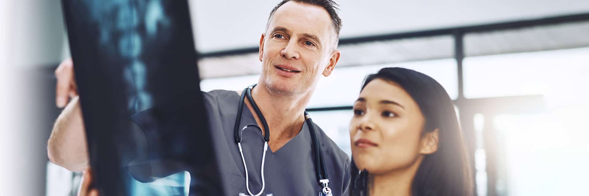 Man and young women in scrubs looking at x-rays.
