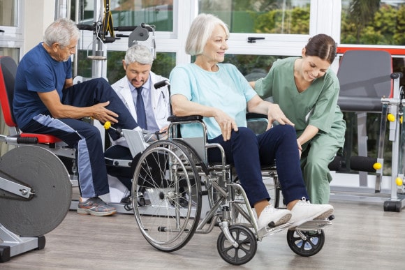 physical-therapy-aide-and-doctor-assisting-seniors-in-wheelchairs