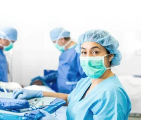 A masked surgical team in blue scrubs prepares for a procedure in an operating room.